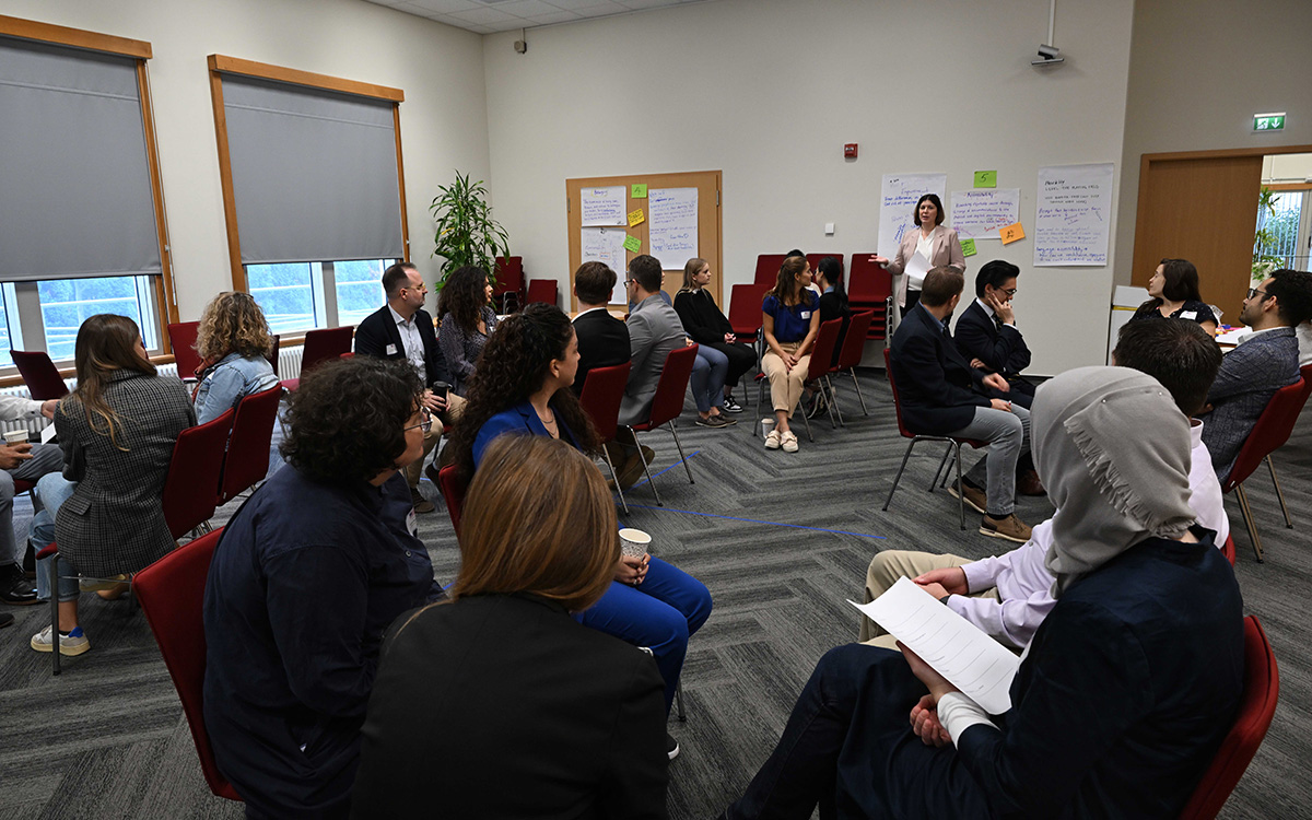 Victoria Mitchell Avdiu leads a coaching training session with participants seated in discussion groups at the U.S. Consulate Frankfurt.