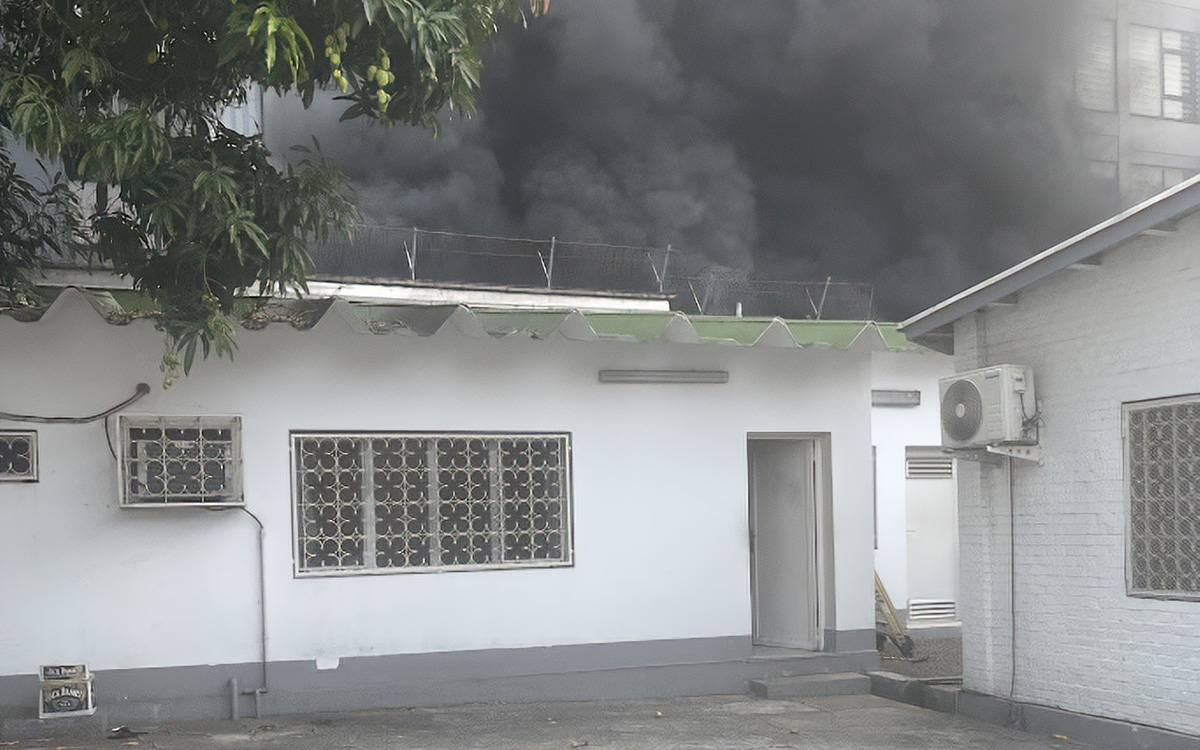 Thick black smoke rises behind buildings near the author’s residence in DR Congo.