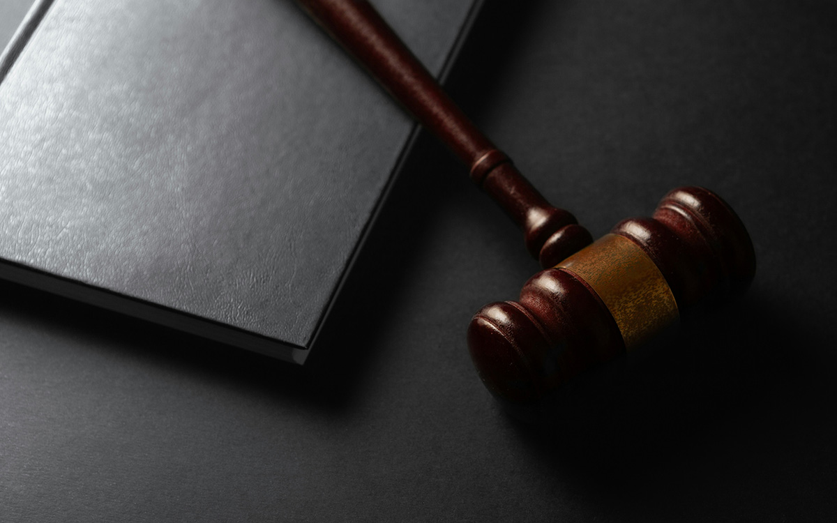 wooden gavel resting on a dark surface next to a book